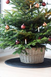 dekorerad julgran med belysning, julgransmatta i svart och korgen smart