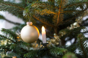 Julgranskula i guldfärg och julgransbelysning